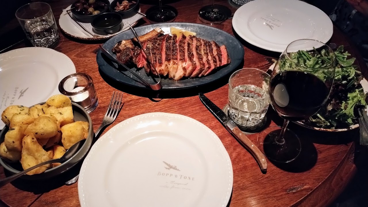Shared Bopp & Tone table with steak, potatoes, salad and wine